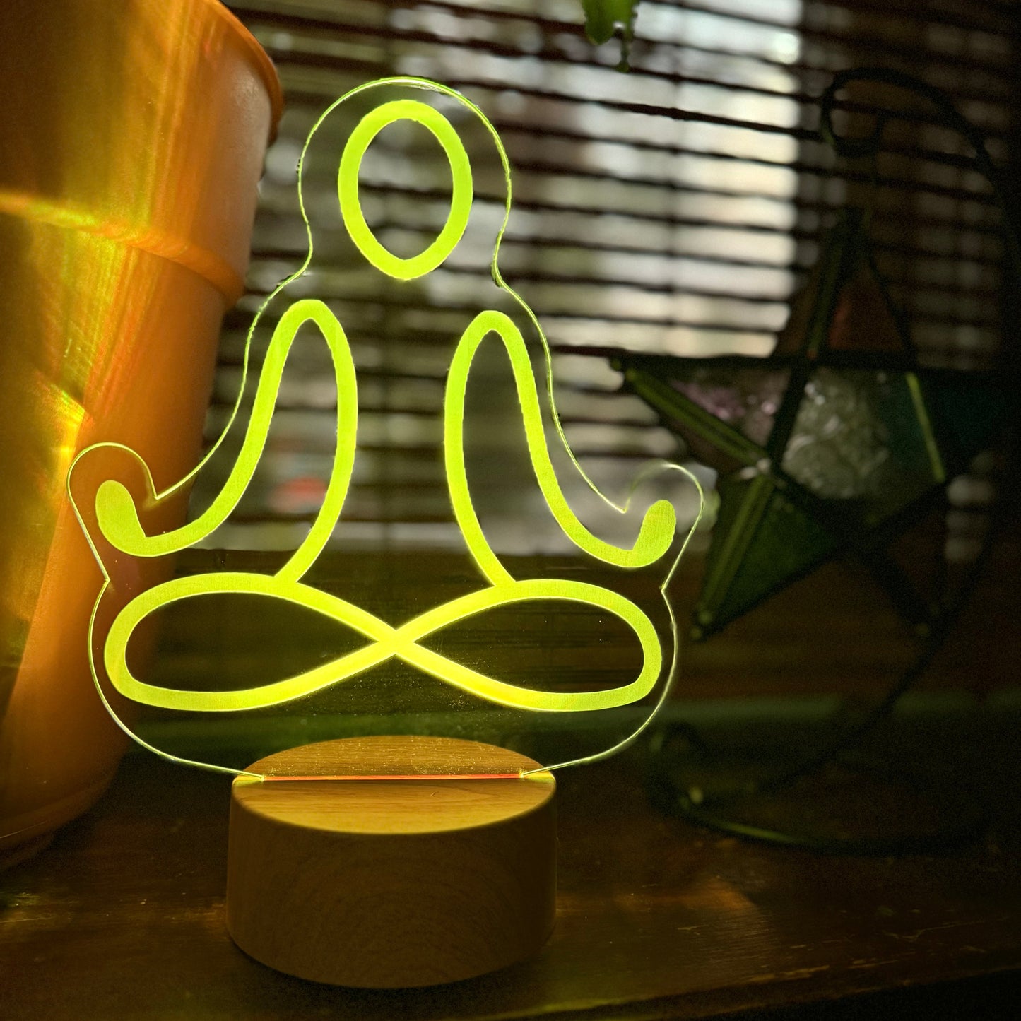 Neon light shaped like a person in a meditative pose on a wooden surface.