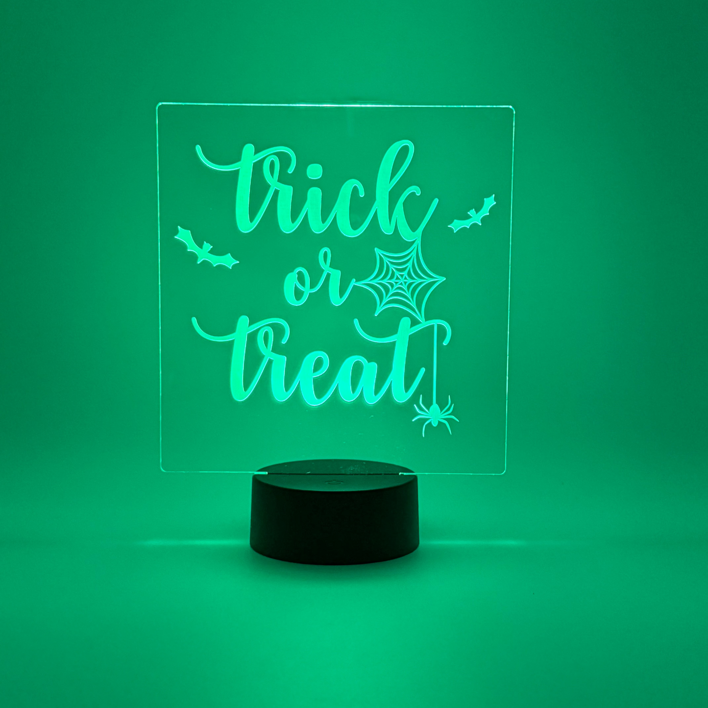 Glowing green LED sign with 'trick or treat' text on a green background