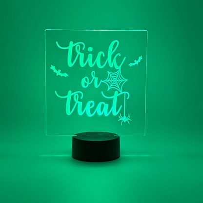 Glowing green LED sign with 'trick or treat' text on a green background