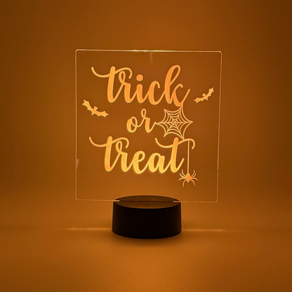 LED sign with 'Trick or Treat' text on a black base against an orange background